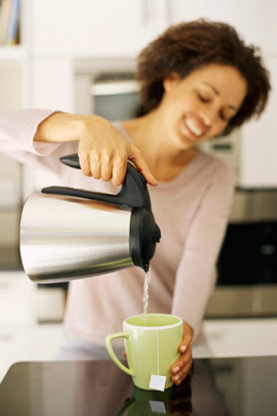 Woman pouring coffee and smiling in kitchen