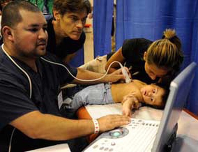 Dr. Oz treats a baby at the free clinic.