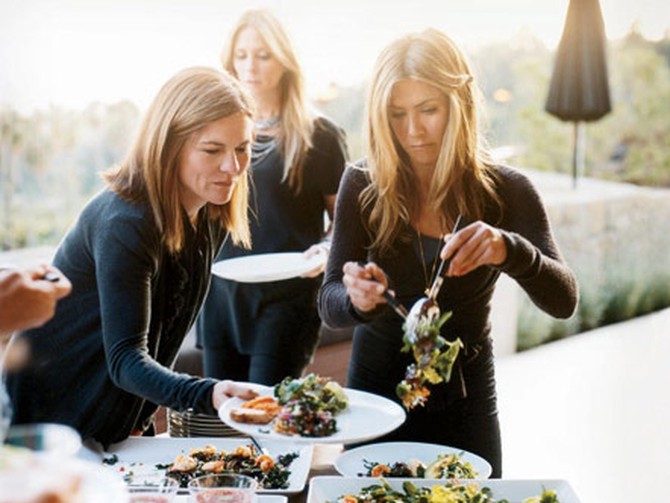 Jennifer Aniston serving salad to Kristin Hahn