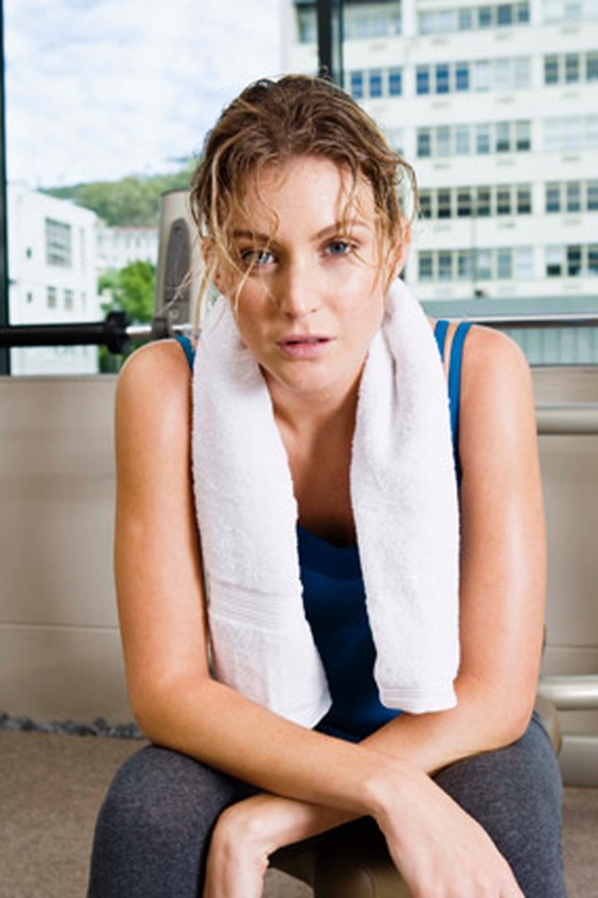Sweaty woman with messy hair looking tired at the gym