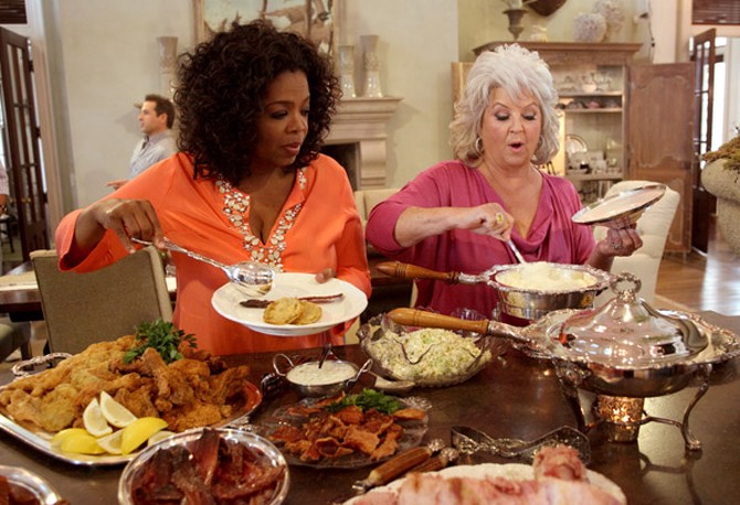 Oprah Winfrey and Paula Deen serving themselves food from a buffet