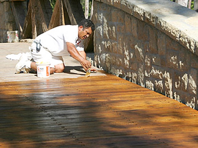 A worker stains and seals the bridge.