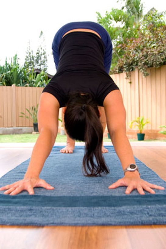 Woman doing downward-dog yoga pose on mat
