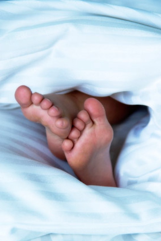 Bare feet peeking out of covers in bed