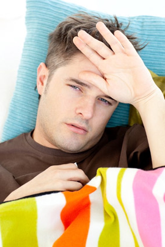 Man feeling hot, sweaty and uncomfortable in bed