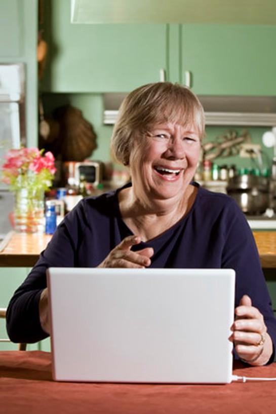 Woman laughing while looking at laptop