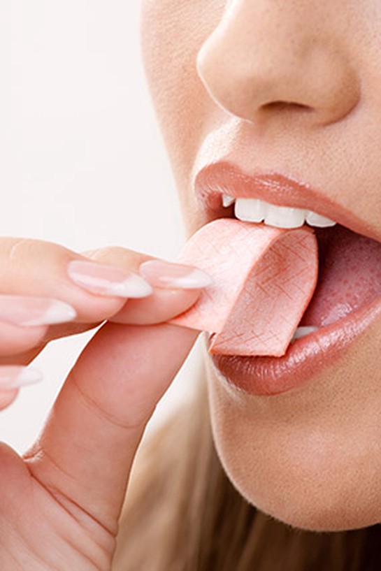 Woman inserting stick of gum into mouth