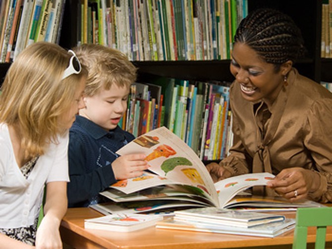 Woman helping children read