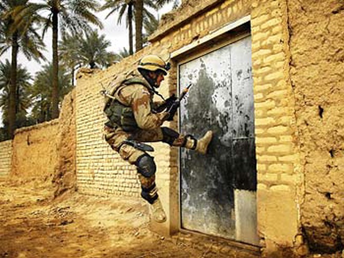 A soldier breaks down a door.
