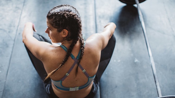 Woman with braids sitting on weight lifting mat