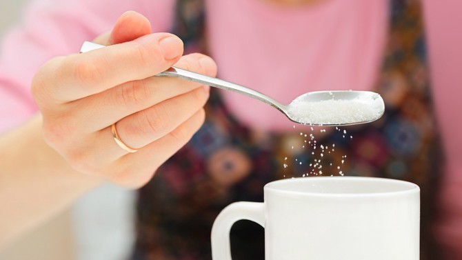 Women pouring sugar into a mug