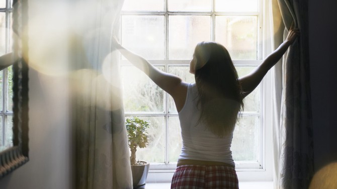 Woman opening curtains in the morning