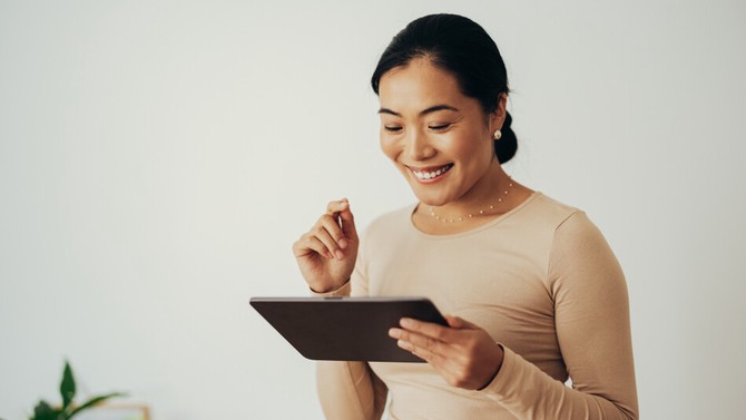 woman smiling while using tablet