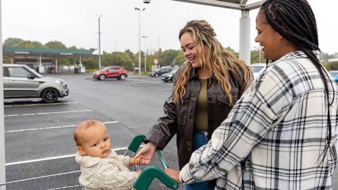 woman approaches her friend and her baby in a parking lot
