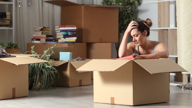 woman feeling sad unpacking boxes in her new apartment