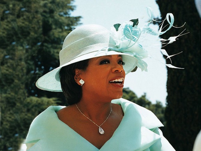 Oprah wearing a hat of feathers and silk roses