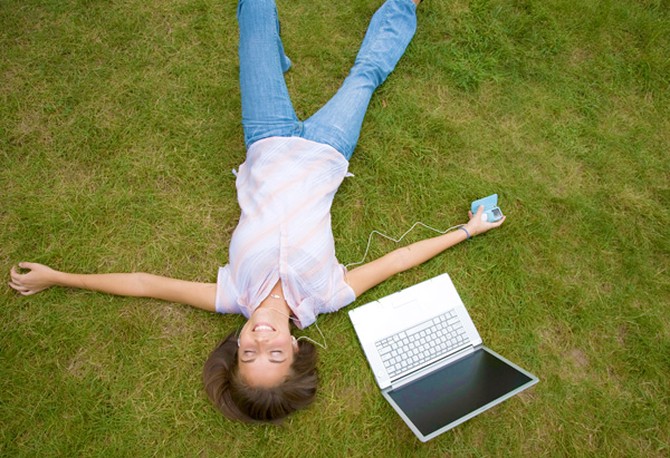 Woman with laptop relaxing in the grass