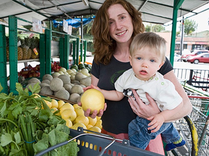 Mother shopping for fruit with her baby