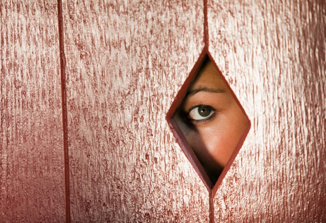 Woman looking through hole in fence
