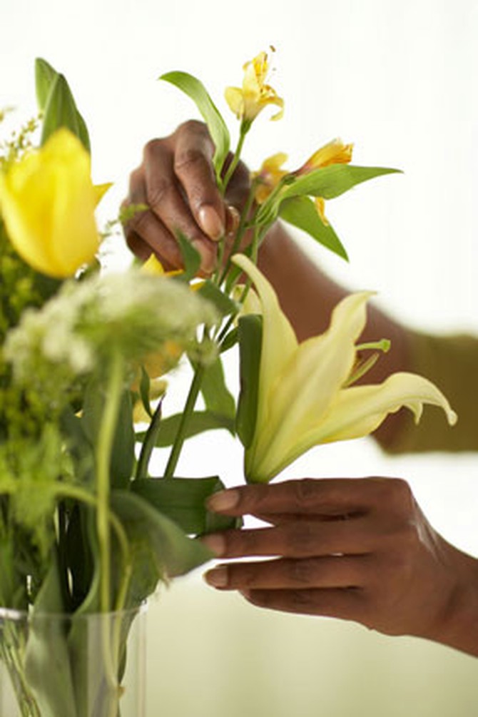 Woman's hand arranging flowers in vase