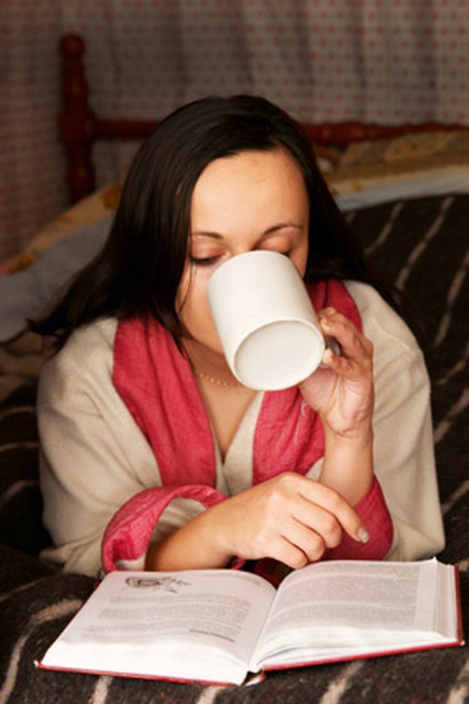 Woman drinking tea reading book staying up late
