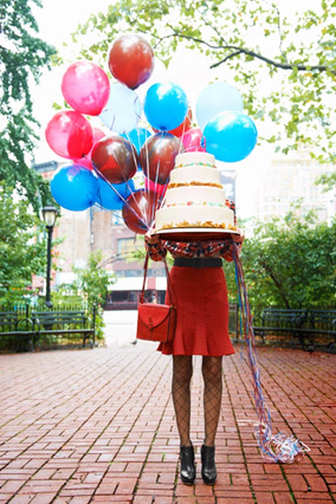 woman in trumpet skirt carrying a birthday cake