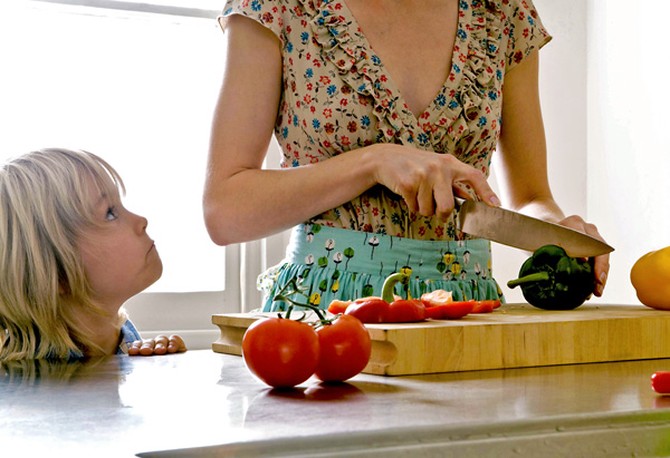 Parent cutting vegetables while the child watches