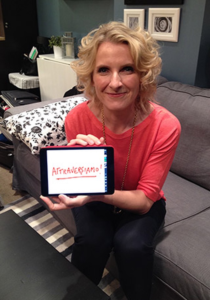 Elizabeth Gilbert holding computer tablet that says, "Attraversiamo!"