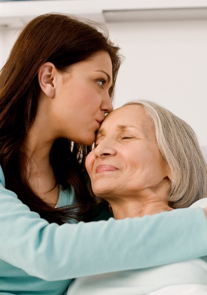 Woman kissing mother's forehead
