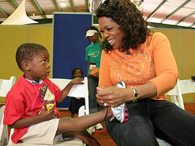 Oprah helps a child with his new shoes.