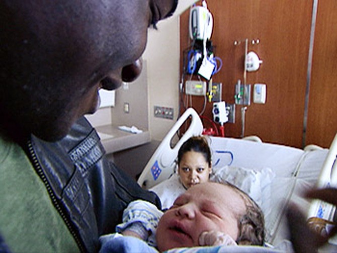 Sheg holds a newborn at Denver Health's Newborns in Need.
