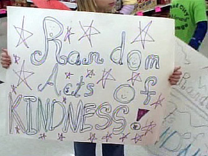 Before helping to carry groceries to cars, Brownies hold up signs they made.