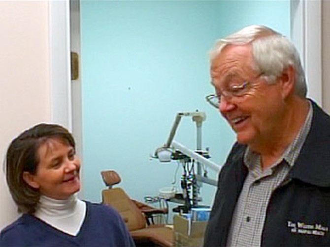 Ann Nowak gives her challenge money to retiring dentist Dr. Lee Bomgaars for a dental clinic he started for needy children.