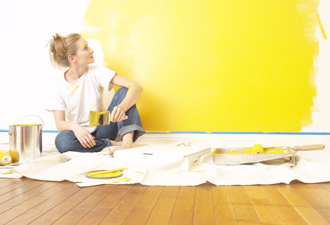 Woman painting wall yellow