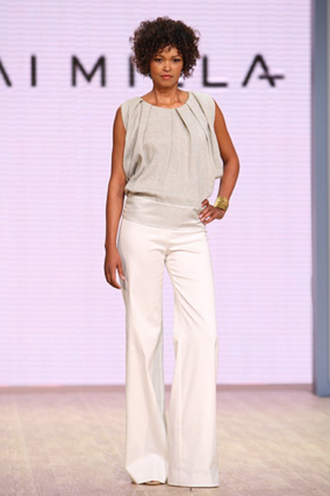 A light gray rough linen pleated top and white stretch boot-cut pants.