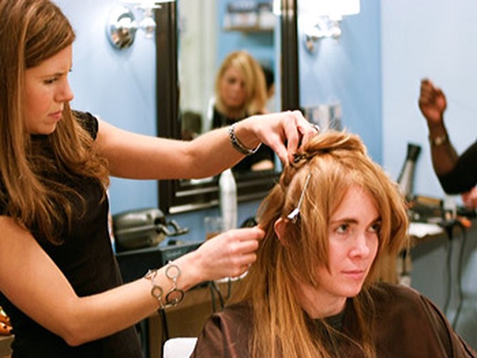 A hairstylist works on attaching some hair extensions.