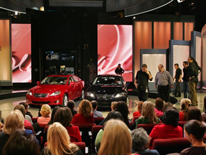 Cars are arranged before Oprah parallel parks onstage.