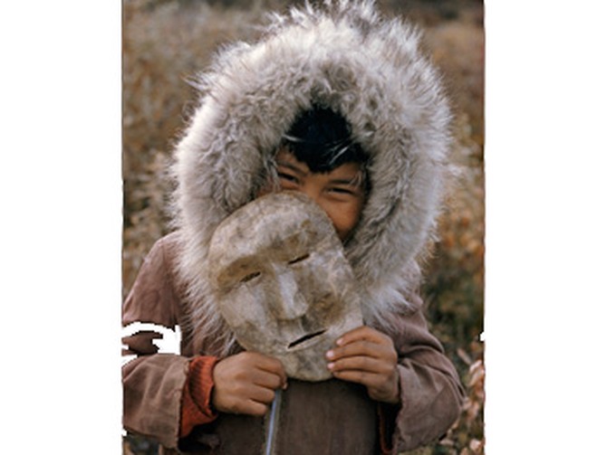 A Nunamiut boy holds a mask made of caribou hide